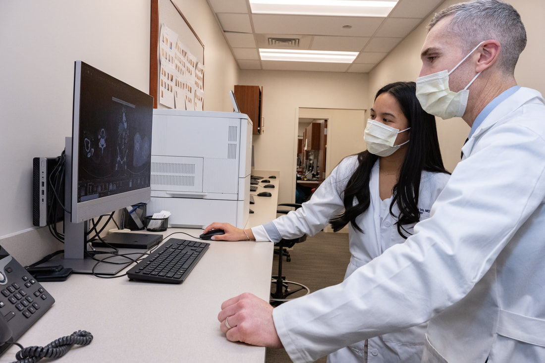 physicians wearing masks looking at a computer