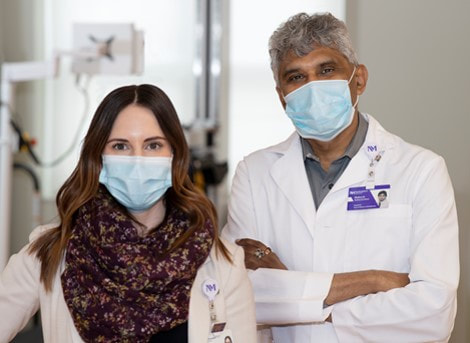 Photo of Vanessa Flaherty, PT and Dr. Mahesh Ramachandran in hallway wearing masks